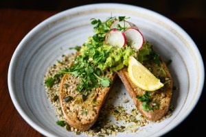 Brotscheiben mit grüner Guacamole und Radieschen